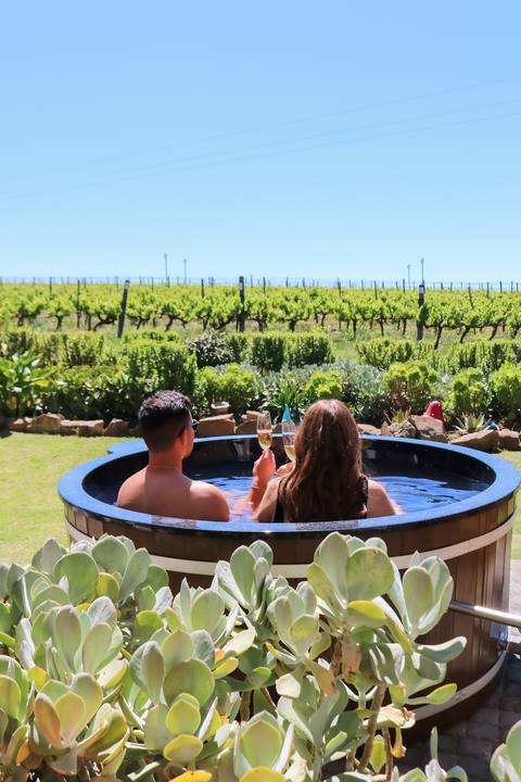 A couple relaxing in the wooden hot tub among the vines