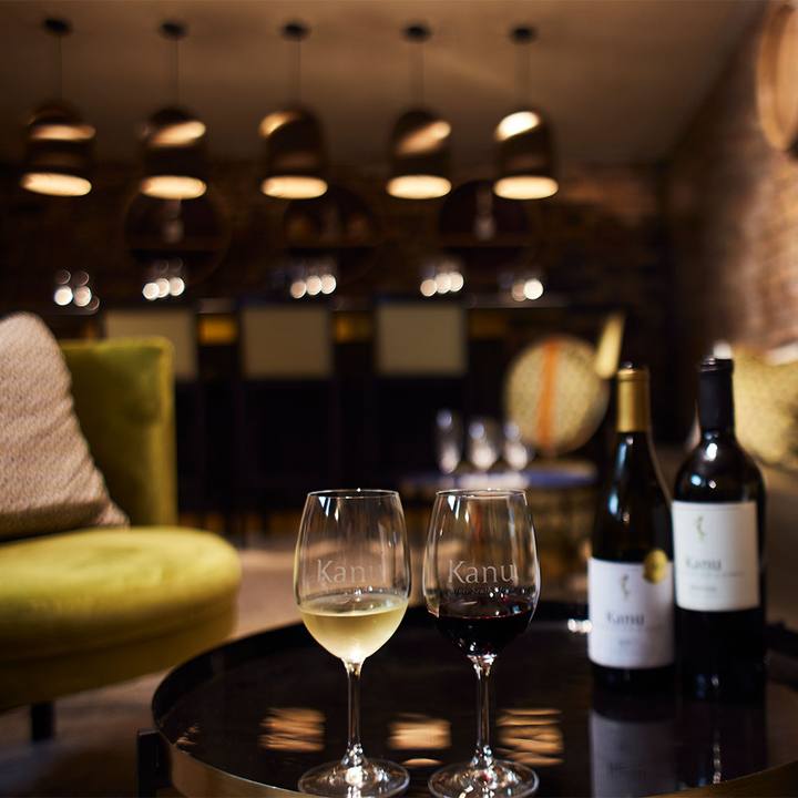 Wine glasses and bottles on a lounge table beneath pendant lights