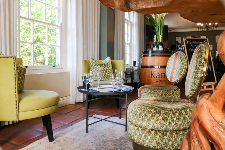 Lounge with armchairs and a barrel table beside tall windows