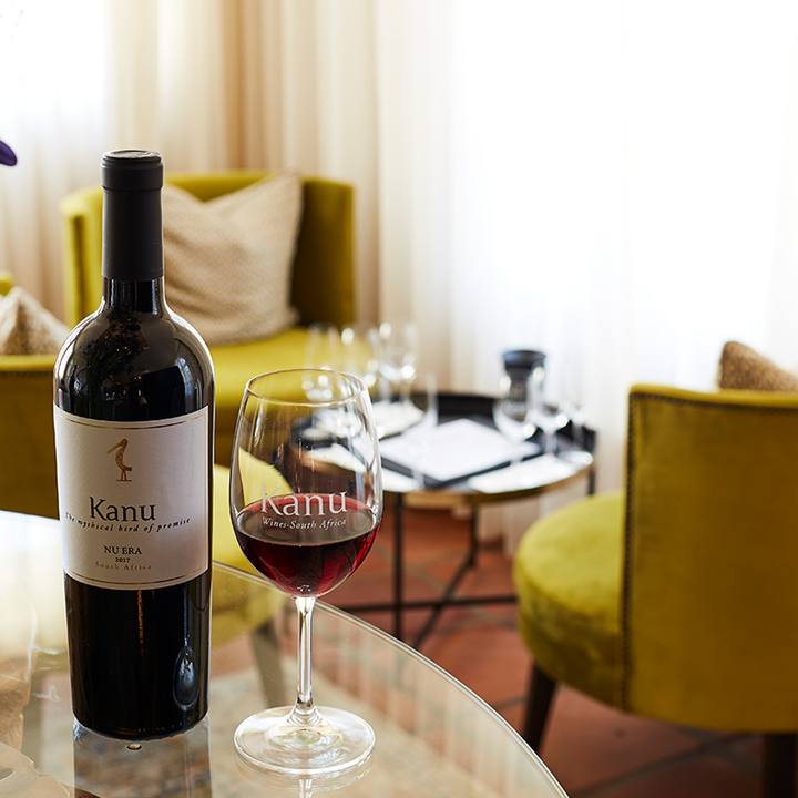 A bottle and a glass of red wine on a lounge table